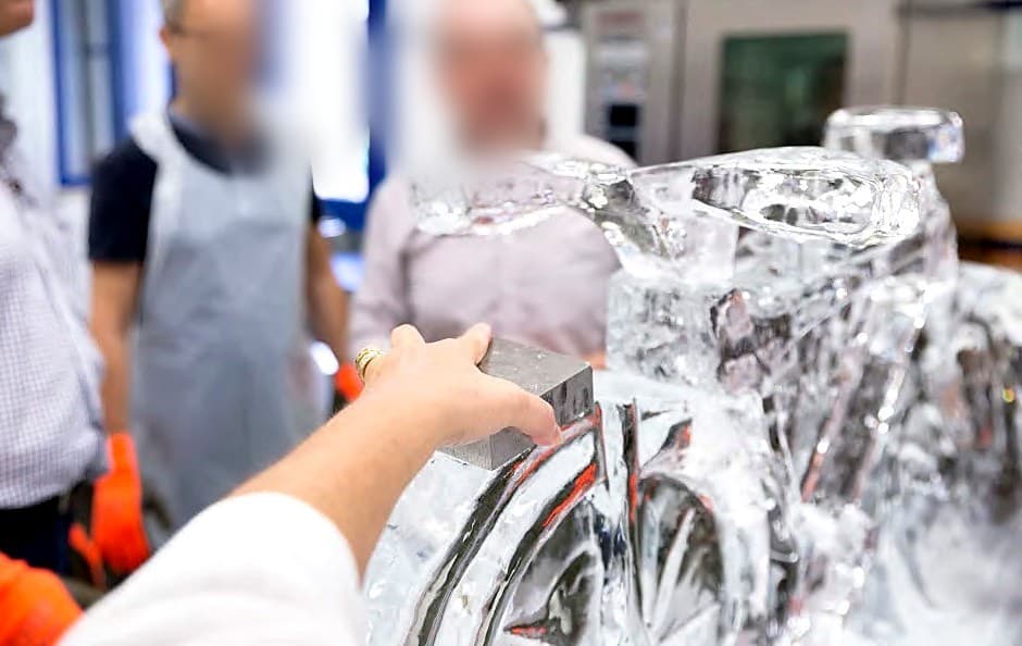 Una mano usa un blocchetto di alluminio per unire due parti della scultura di ghiaccio