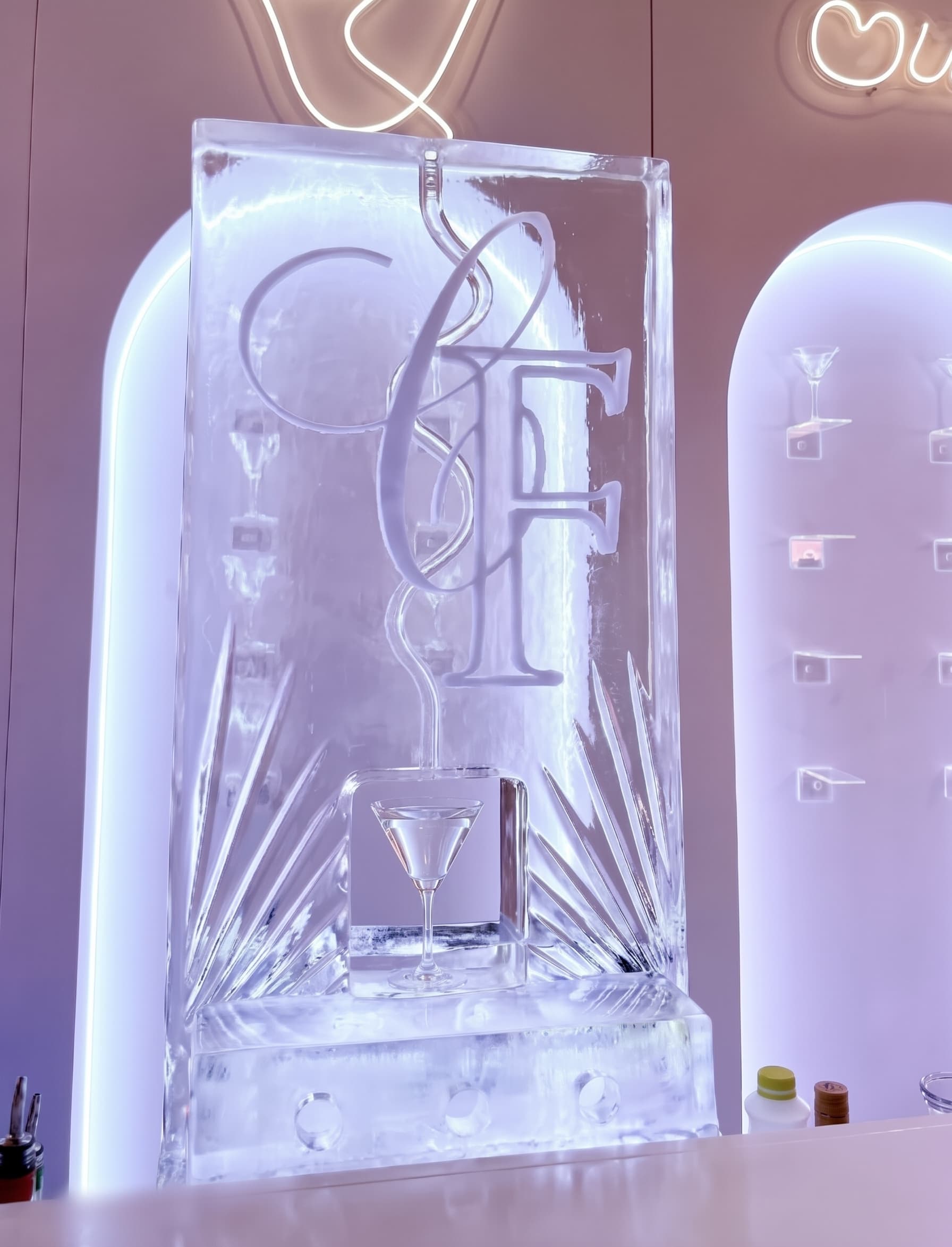 Scivolo di ghiaccio con monogramma scolpito e canale per il drink che termina in un bicchiere da cocktail alla base